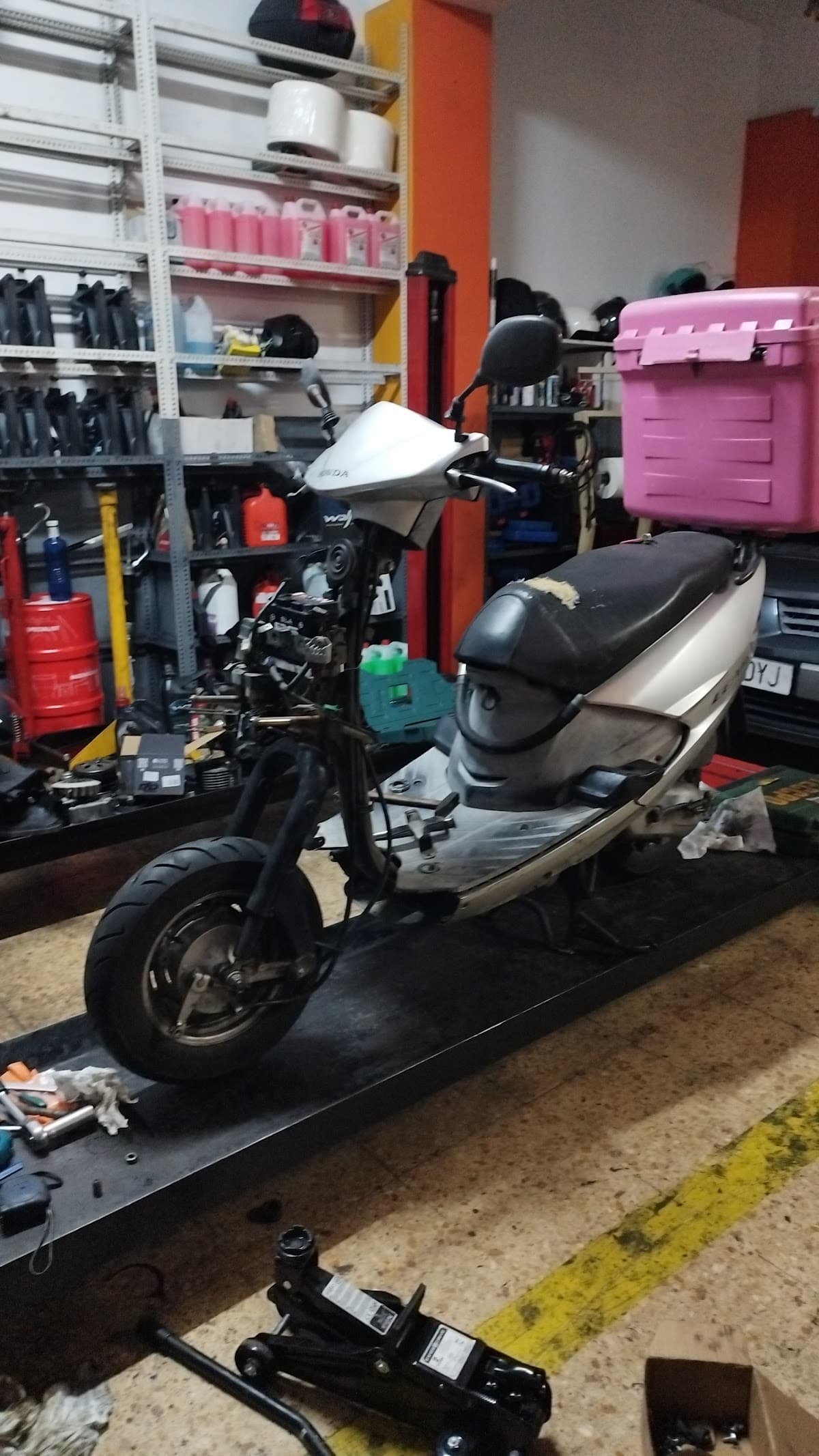 Zona de trabajo del taller YOCOMOTORS con estanterías de recambios y vehículos en reparación